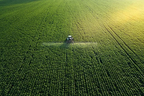 Tractor plowing vast green fields, representing ESG for equipment finance.