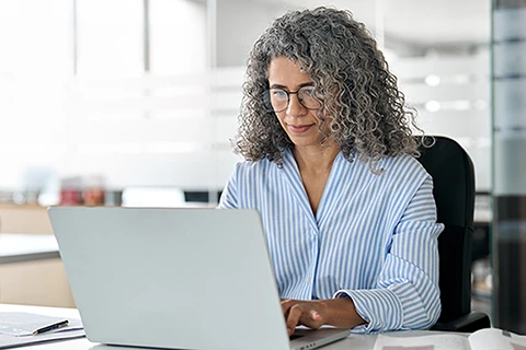 An asset finance professional working on a laptop considering adding as-a-service offerings.